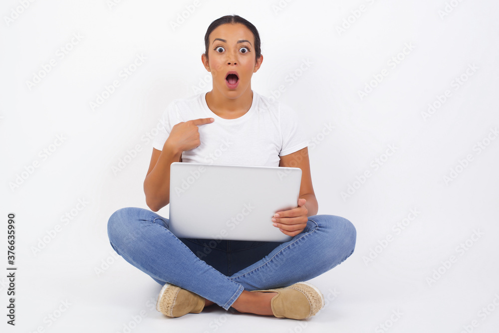 Surprised beautiful female student being in stupor shocked, has astonished expression pointing at herself with finger saying: Who me? Isolated over gray background. Surprised beautiful female student being in stupor shocked, has astonished expression pointing at herself with finger saying: Who me? Isolated over gray background.