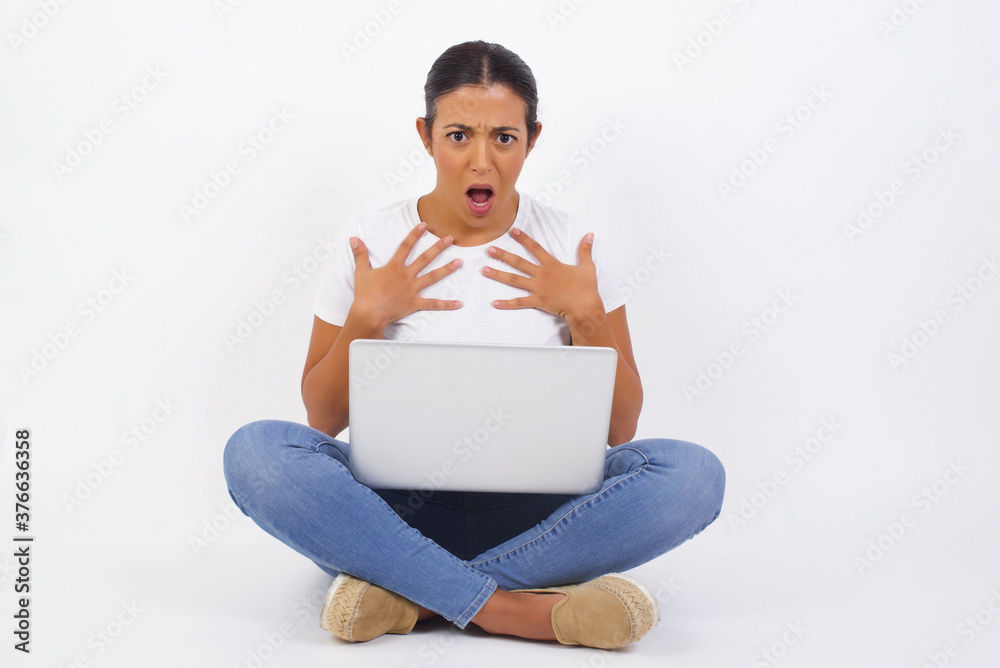 Shocked scared beautiful young woman keeps hands on chest, mouth widely opened, stares at camera realizes that she forgot to pay bills, receives big fine, isolated outdoors. Girl saying: Who, me? Shocked scared beautiful young woman keeps hands on chest, mouth widely opened, stares at camera realizes that she forgot to pay bills, receives big fine, isolated outdoors. Girl saying: Who, me?