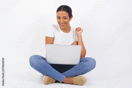 Image of cheerful pretty young caucasian lady standing against gray wall with hand near face. Looking with glad expression at the camera after listening to good news. Confident girl.