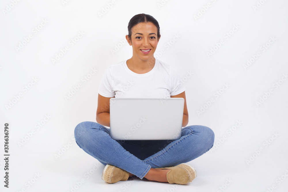 Close up studio shot of beautiful young mixed race woman model with curly dark hair looking at camera with charming cute smile while posing against white blank copy space wall for your content Close up studio shot of beautiful young mixed race woman model with curly dark hair looking at camera with charming cute smile while posing against white blank copy space wall for your content