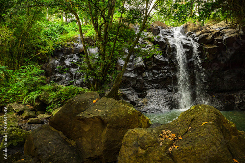 Waterfall landscape. Beautiful hidden waterfall in tropical rainforest. Foreground with big stones. Fast shutter speed. Sing Sing Angin waterfall, Bali, Indonesia