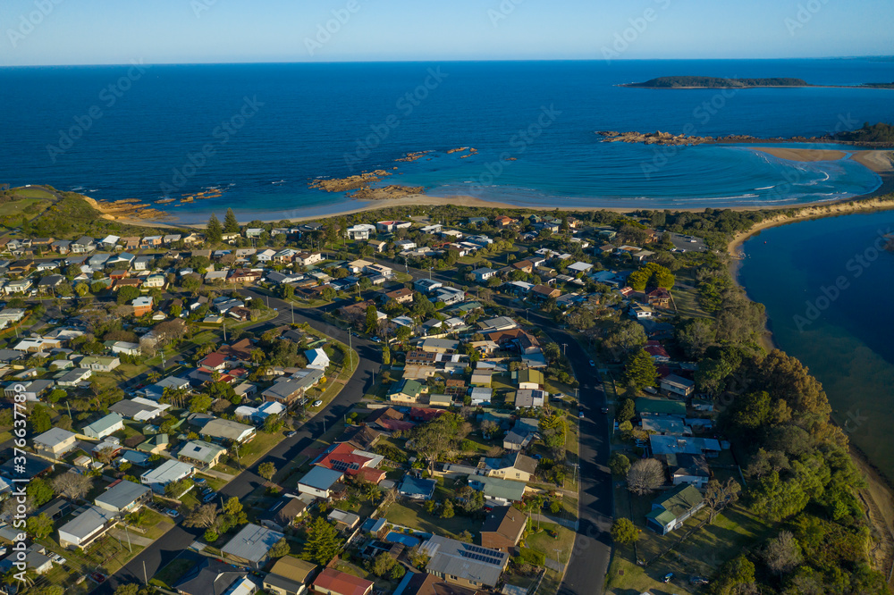 Panoramic aerial view of the beautiful town centre of Tomakin toward Tomakin Beach, Tomaga River and Melville Point on the New South Wales South Coast, Australia in the late afternoon