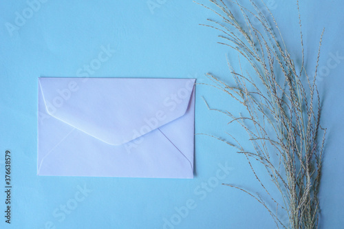 white envelope with dried grass for greeting mockup seasonal concepts on blue background