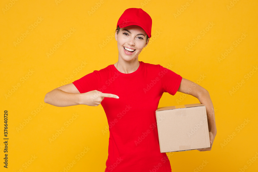 Delivery employee woman in red cap blank t-shirt uniform work courier in service during quarantine coronavirus covid-19 virus holding giving cardboard box isolated on yellow background studio portrait Delivery employee woman in red cap blank t-shirt uniform work courier in service during quarantine coronavirus covid-19 virus holding giving cardboard box isolated on yellow background studio portrait