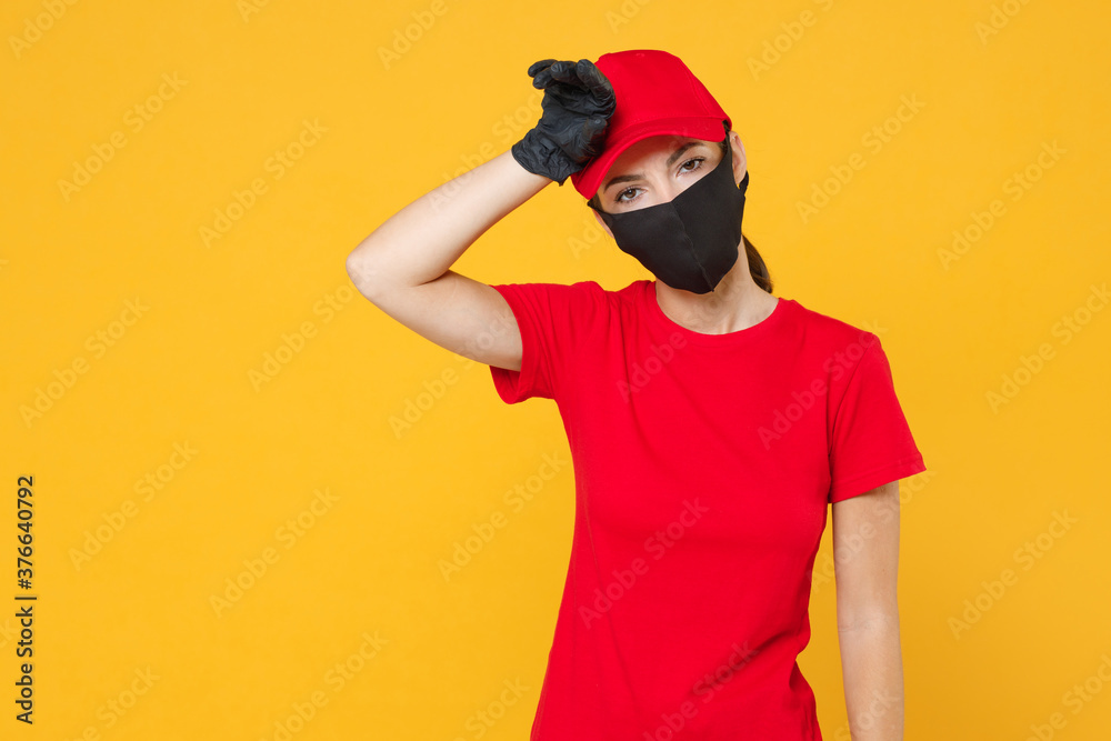 Delivery employee woman in red cap blank t-shirt uniform protect face mask gloves working courier in service during quarantine coronavirus covid-19 virus isolated on yellow background studio portrait. Delivery employee woman in red cap blank t-shirt uniform protect face mask gloves working courier in service during quarantine coronavirus covid-19 virus isolated on yellow background studio portrait.