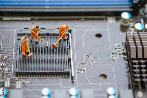 Miniature People: Worker cleaning professional repairman holding a cleaning brush inside old personal computer. CPU cleaning and maintenance concept, close up view..