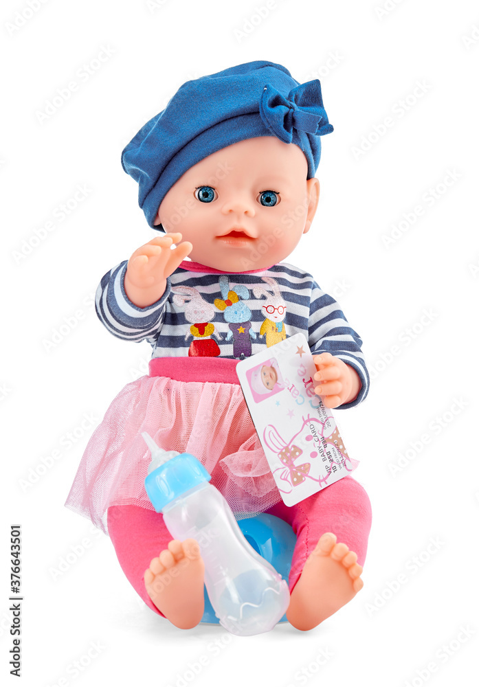 Plastic doll girl in bright fancy clothes sits on a baby pot with a toy children's ID card in her hand and a milk bottle isolated on a white background.