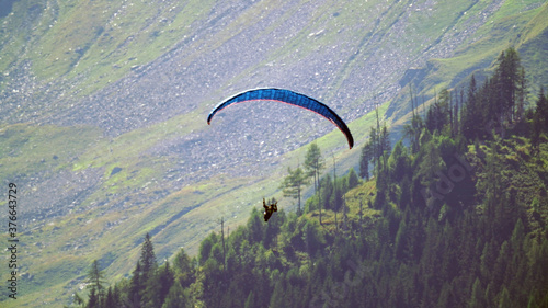 a paraglider in the air in the mountains
