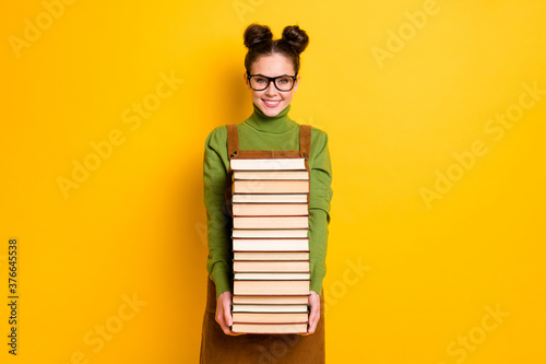 Portrait of her she attractive brainy diligent cheerful girl nerd carrying many book 1 September new year semester grade isolated bright vivid shine vibrant yellow color background photo