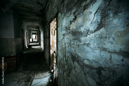 Eerie atmosphere in an abandoned building with huge windows and spider webs and one lamp. Halloween themed image. 