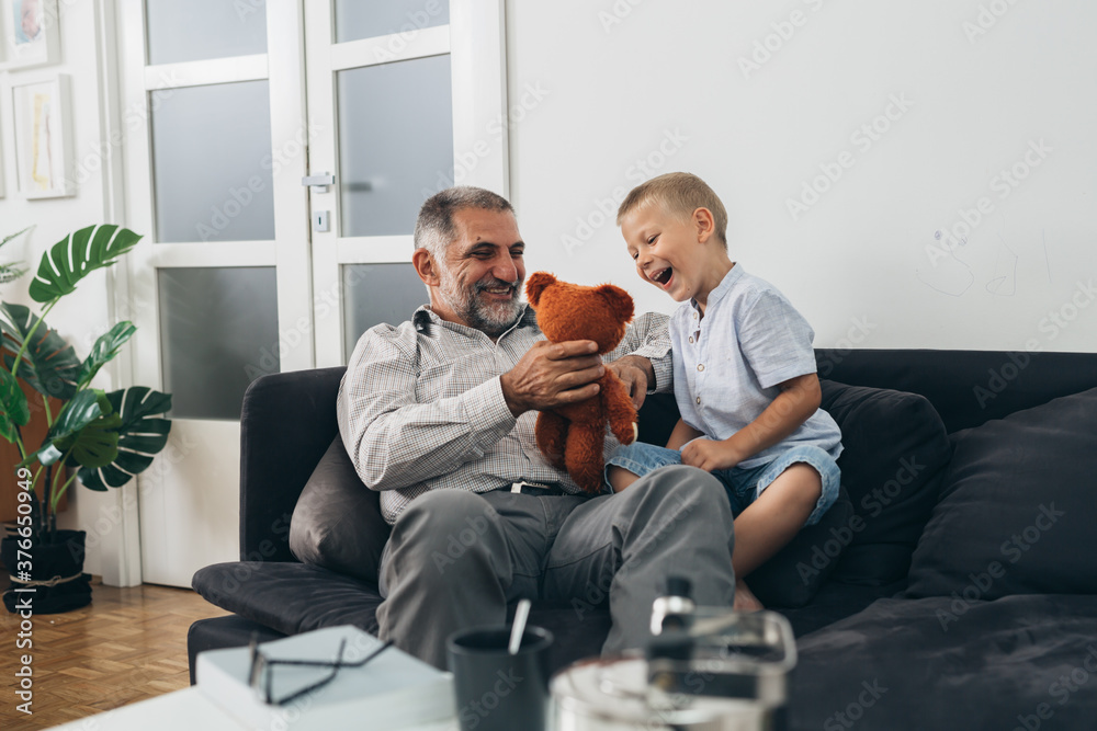 grandfather and his grandson relaxing on sofa playing with toys grandfather and his grandson relaxing on sofa playing with toys