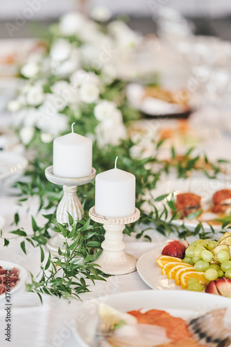 White candles in candlesticks at a wedding celebration. High-quality photo