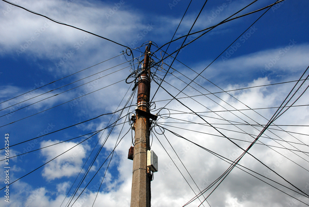 Electric pole with many wires against the blue cloudy sky Electric pole with many wires against the blue cloudy sky