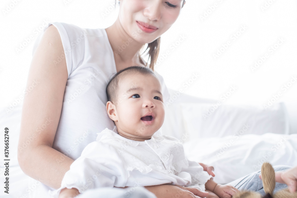 Bright portrait of happy mum holding infant child on hands. Mother hugging her little. happy loving family. mother playing with her baby in the bedroom. Love, trust and tenderness concept. Bright portrait of happy mum holding infant child on hands. Mother hugging her little. happy loving family. mother playing with her baby in the bedroom. Love, trust and tenderness concept.