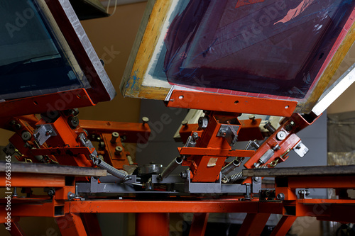 Print screening apparatus. serigraphy production. printing images on t-shirts in a design studio.