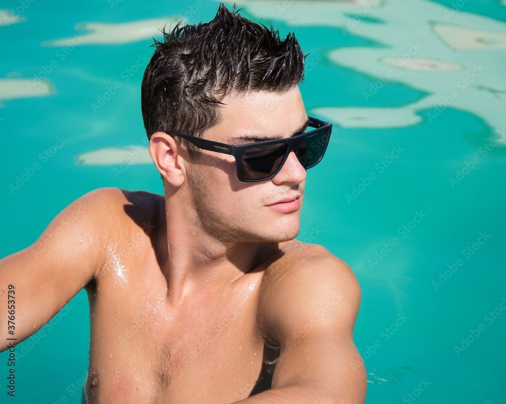 Summer. Young attractive guy in the pool.