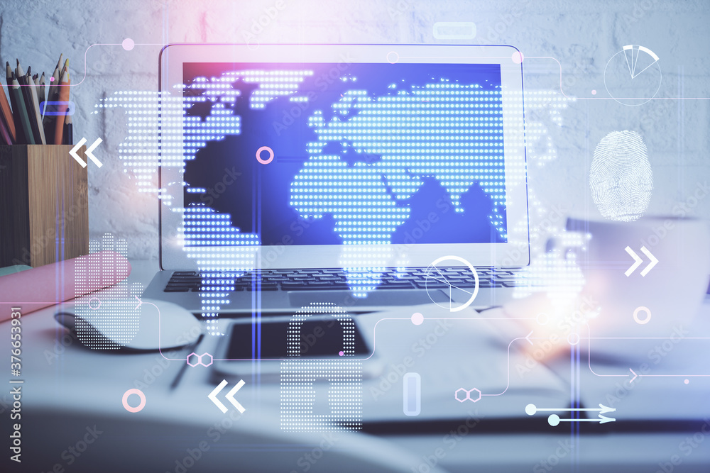 Double exposure of desktop with computer and world map hologram. International data network concept.