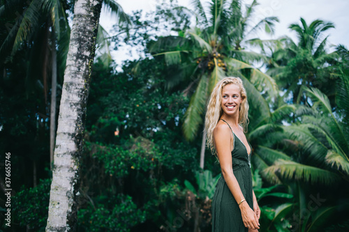 Happy beautiful female standing by tropical trees