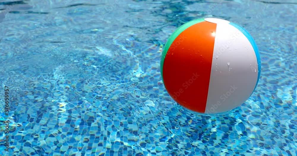 Beach ball in pool. Colorful inflatable ball floating in swimming pool, summer vacation concept.
