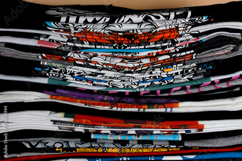 selective focus photo of t-shirts with bright prints, printed by silkscreen. serigraphy production. printing images on t-shirts in a design studio.