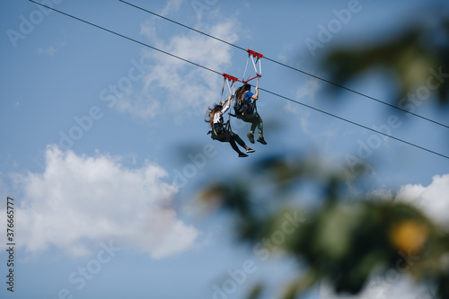 a brave man descends on a zip line high in the mountains above the forest