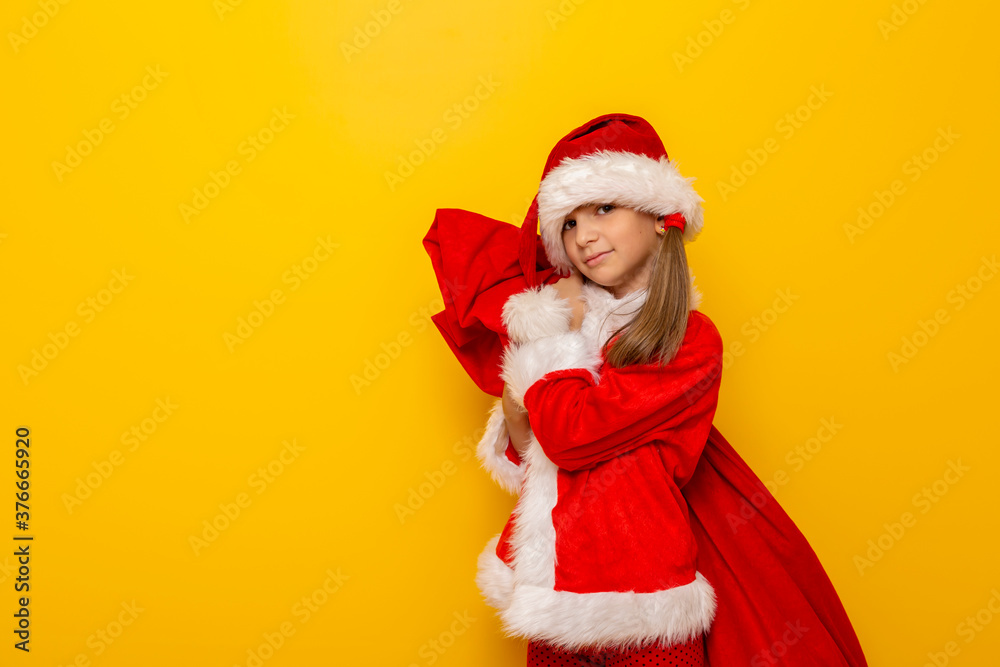 Child in Santa costume carrying a sack of Christmas presents