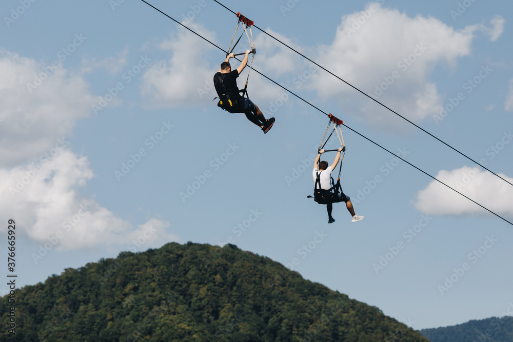 a brave man descends on a zip line high in the mountains above the forest a brave man descends on a zip line high in the mountains above the forest