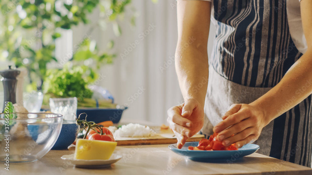 Close Up Shot of a Man Putting a Chopped Tomato in a Bowl. Preparing a Healthy Vegetarian Organic Salad Meal in a Modern Kitchen. Natural Clean Diet and Healthy Way of Life Concept.