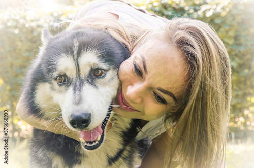 attractive blonde hugs her dog in the park.