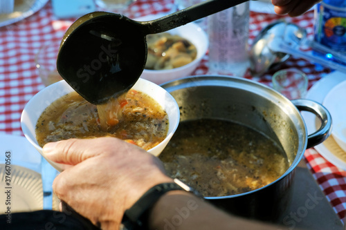 Man pouring traditional polish soup flaki 