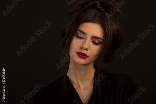 brunette with an elegant hairstyle and beautiful makeup on a black background. close-up 