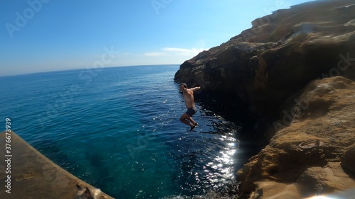 young man jumping in to the sea from a cliff in costa brava