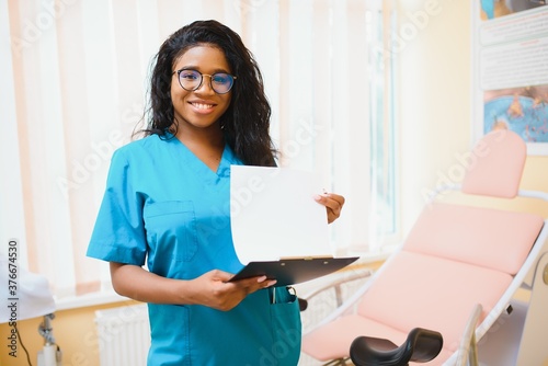 Professional female doctor on blurred consulting room background. African American gynecologist. Gynecology concept.