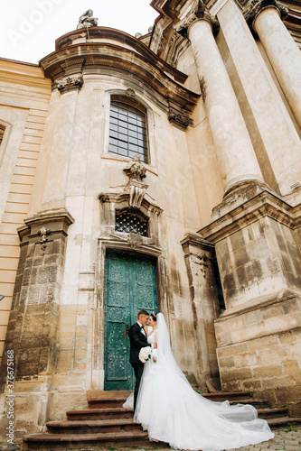 Lovely couple standing on the stairs at the entrance to the church in the Baroque style