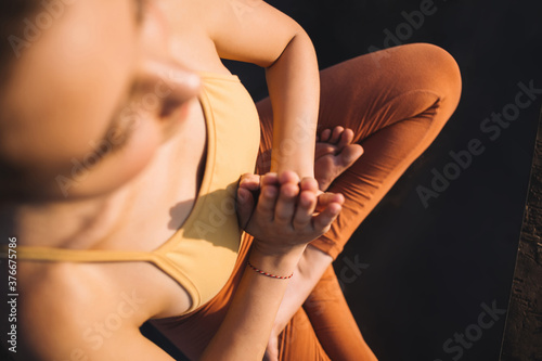 Cropped image on caucasian young 20s woman in activewear sitting in lotus pose keeping hands in namaste for relaxing meditation, top view of tranquil female 20s reaching harmony during yoga practice