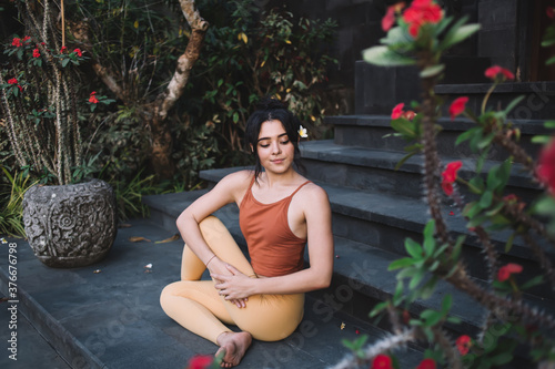 Young woman sitting in Half Spinal Twist pose on steps photo