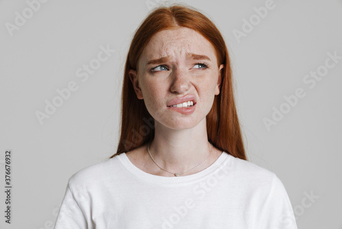 Image of confused ginger beautiful girl looking aside