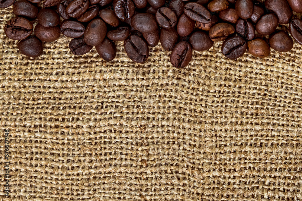 Coffee beans. Macro photo. Sackcloth. Rough fabric texture. Scrim. Coffee beans on sacking. Coffee beans are laid out in a pattern. Coffee abstraction. Flat lay
