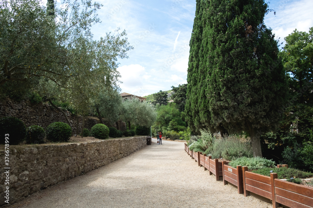 The beautiful backyard with ancient stone architecture and the blossoming garden of the medieval christian abbey in the mountain valley of Pyrenees in France