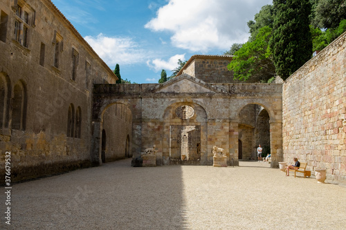 The beautiful backyard with ancient stone architecture and the blossoming garden of the medieval christian abbey in the mountain valley of Pyrenees in France