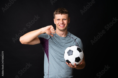Handsome young football player man over isolated black wall © luismolinero