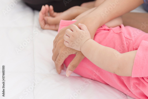 The hand of an infant laying on the hand of the mother lying beside her on the bed represents love and bond.