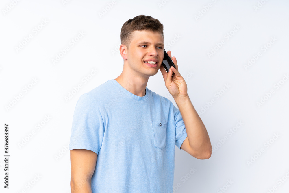 Young handsome man over isolated white background keeping a conversation with the mobile phone Young handsome man over isolated white background keeping a conversation with the mobile phone