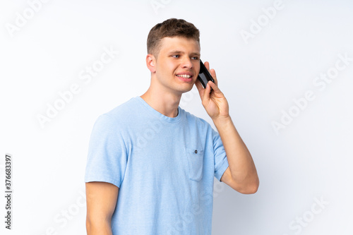 Young handsome man over isolated white background keeping a conversation with the mobile phone