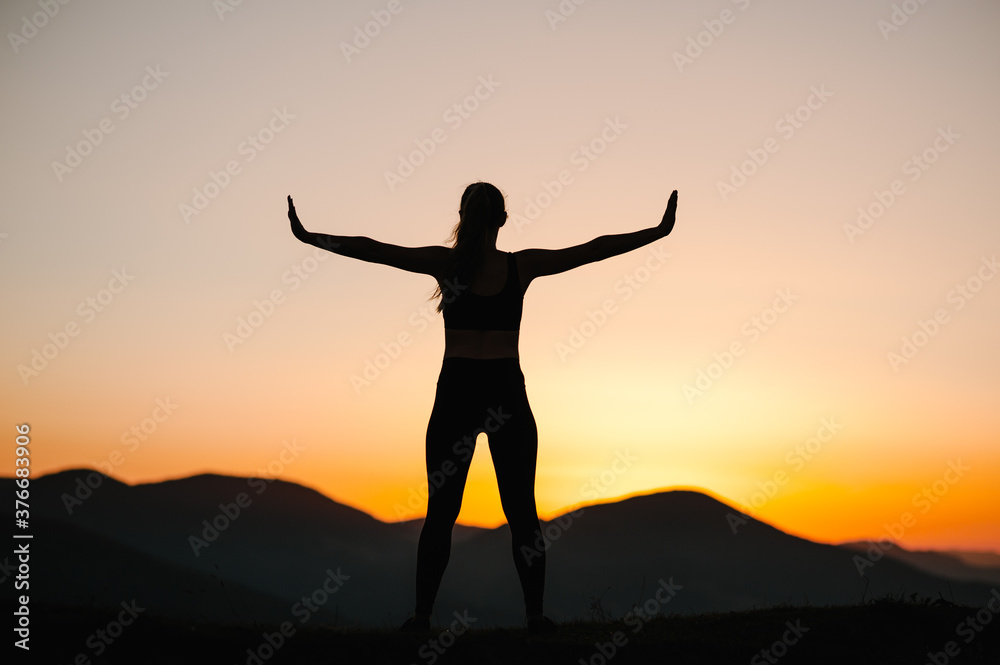 Silhouette woman balanced, practicing meditation, zen energy yoga in mountains. Healthy lifestyle concept. Young girl doing fitness exercise sport outdoors. Morning sunrise. Relax in nature. Back view