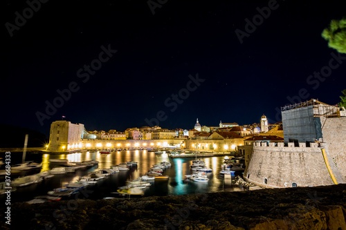 Port with motion blurred boats and light diffraction, long exposure at night. Scenery winter view of Mediterranean old city of Dubrovnik, European travel and historic destination, Croatia