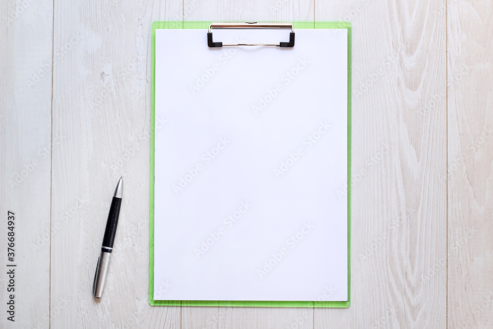 Clipboard with white sheet on wood background. Top view. Clipboard with white sheet on wood background. Top view.