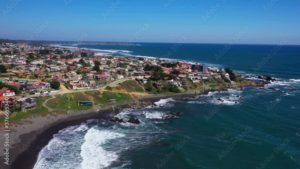 aerial: view of the infiernillo beach in the city of pichilemu also with a view of the city and punta de lobos of black sand and houses on the beach drone shot chile in colchagua cardenal caro