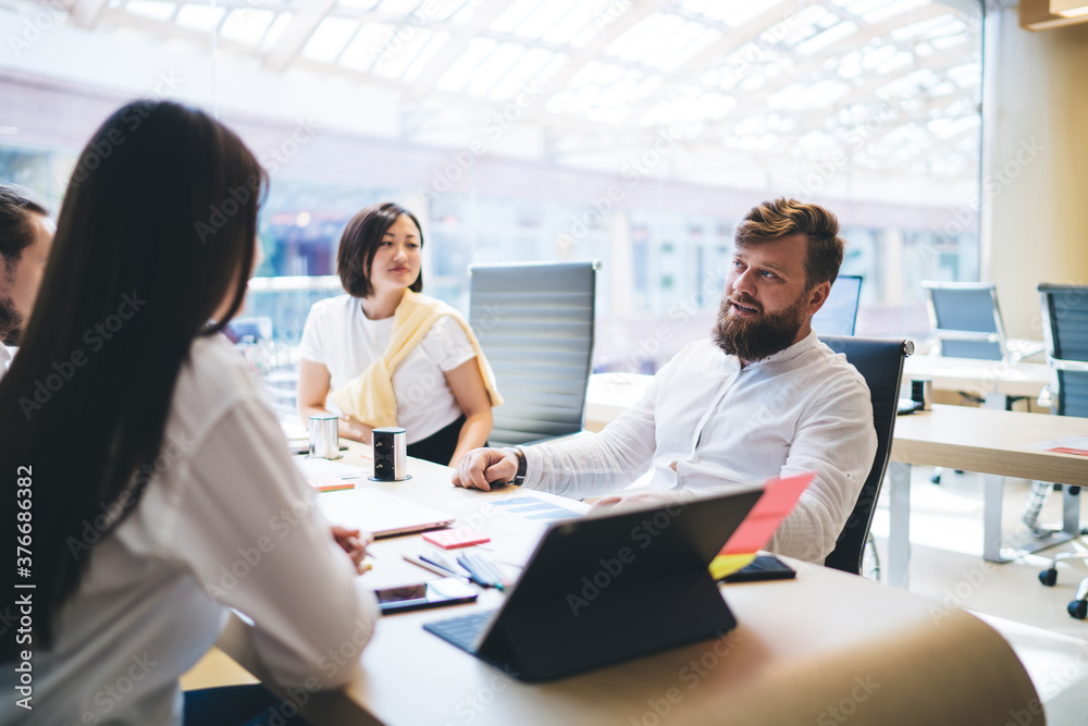 Concentrated male colleague talking about project with diverse coworkers in office Concentrated male colleague talking about project with diverse coworkers in office