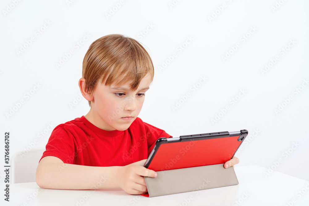 Online education and e-learning concept. School boy using gadget during online lesson. Online education and e-learning concept. School boy using gadget during online lesson.